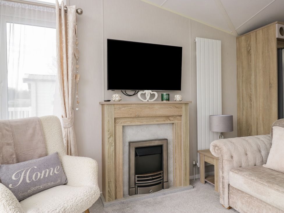A living room with a television and a fireplace at Swan Haven in Grange-Over-Sands