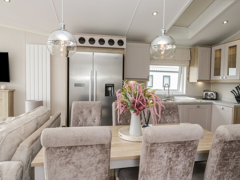 A kitchen with a dining area and a refrigerator at Swan Haven in Grange-Over-Sands