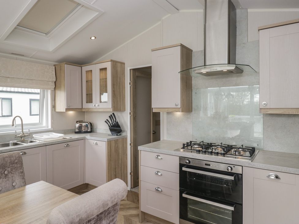 A kitchen with cabinets and appliances at Swan Haven in Grange-Over-Sands