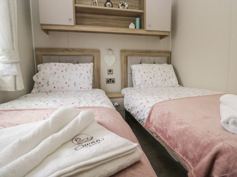 A bedroom with two single beds and towels at Swan Haven in Grange-Over-Sands