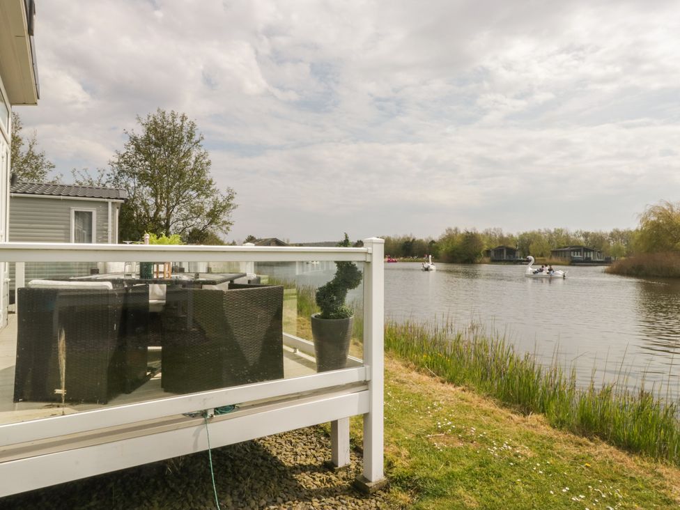 An outdoor patio with furniture overlooking a lake at Swan Haven in Grange-Over-Sands