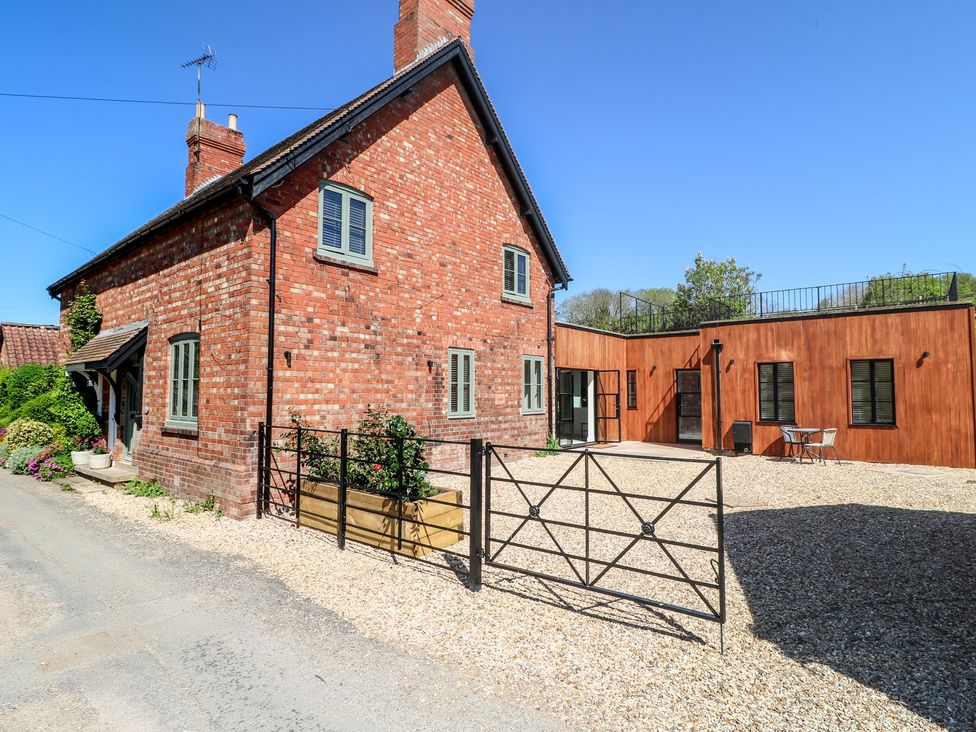 A brick house with a gravel driveway and outdoor seating at Gardener’s Cottage in Oakham