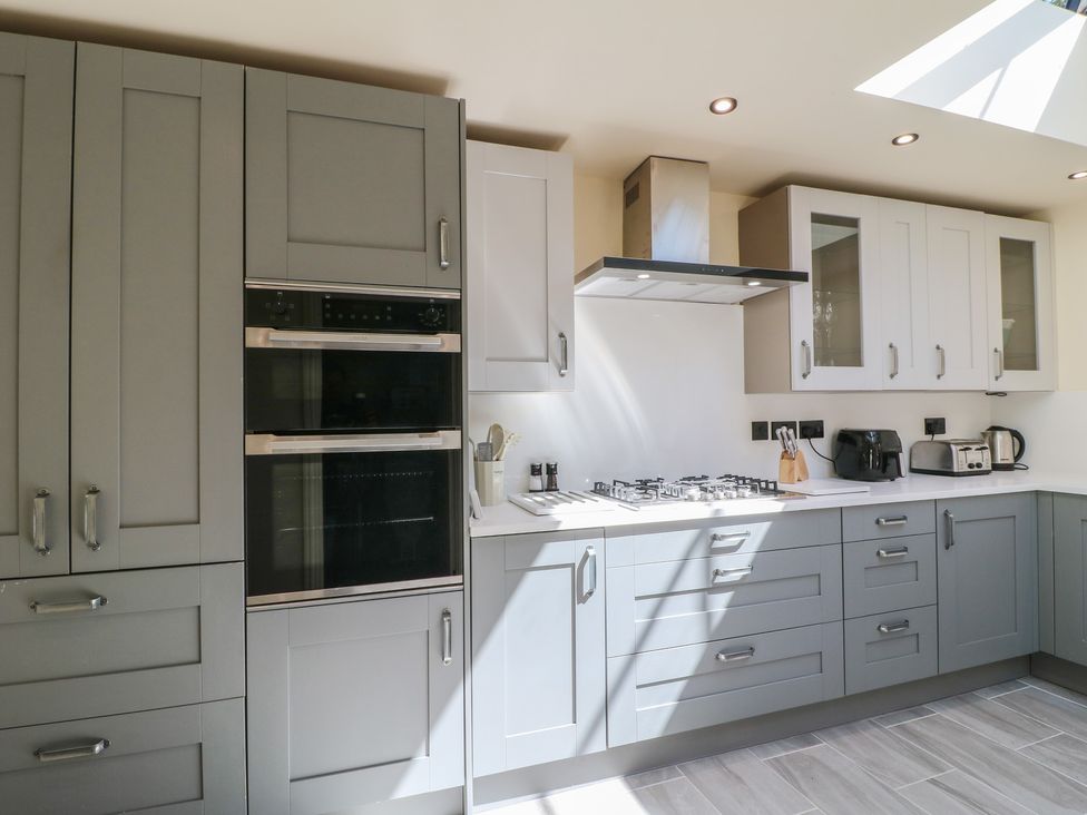 A kitchen with cabinets, oven, gas stove, and countertop at Gardener’s Cottage in Oakham