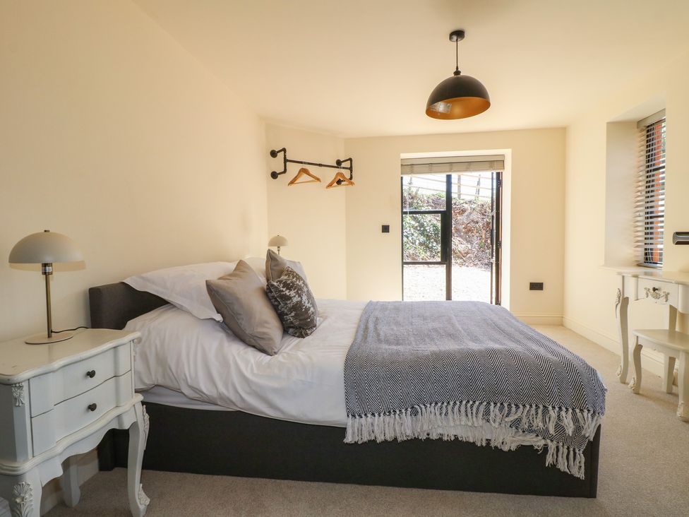 A bedroom with a bed and side table at Gardener’s Cottage in Oakham