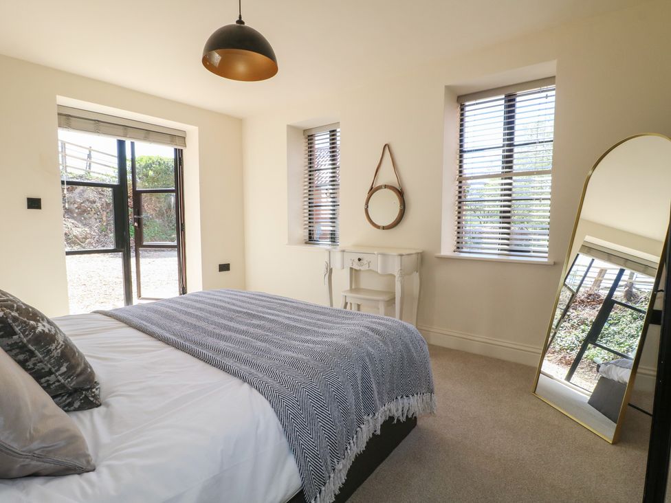 A bedroom with a bed and mirror at Gardener’s Cottage in Oakham