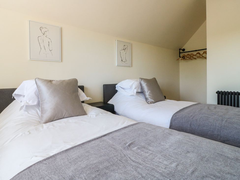A bedroom with two beds and wall art at Gardener’s Cottage in Oakham