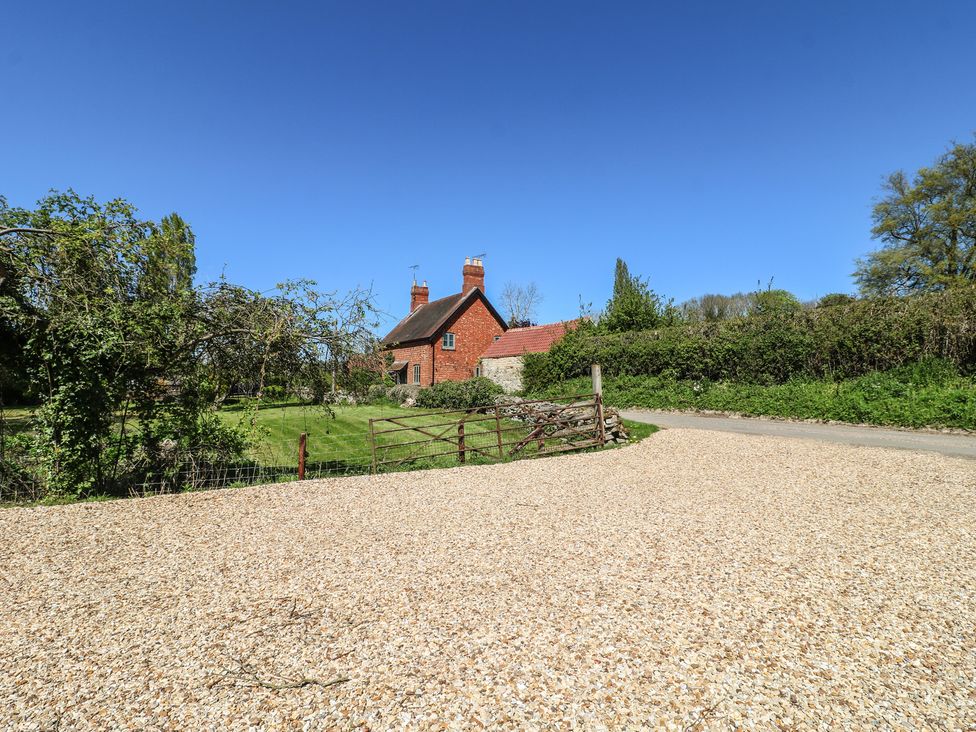 A house with a garden and a gravel driveway at Gardener’s Cottage in Oakham