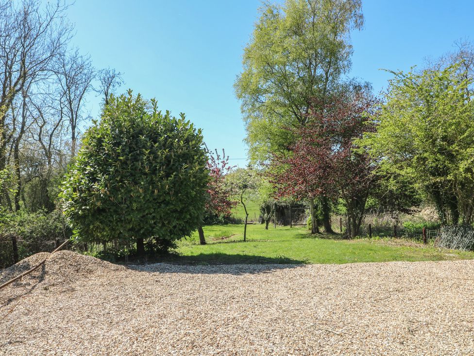 A garden area with trees and a gravel surface at Gardener’s Cottage in Oakham