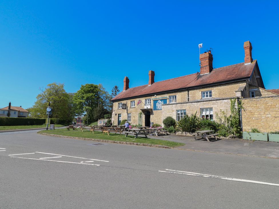 A pub with outdoor seating and trees at Gardener’s Cottage in Oakham