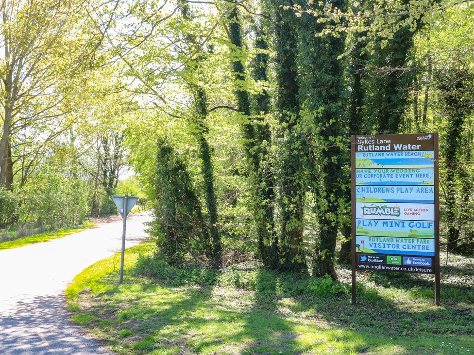 A sign for Sykes Lane at Rutland Water near a path surrounded by trees