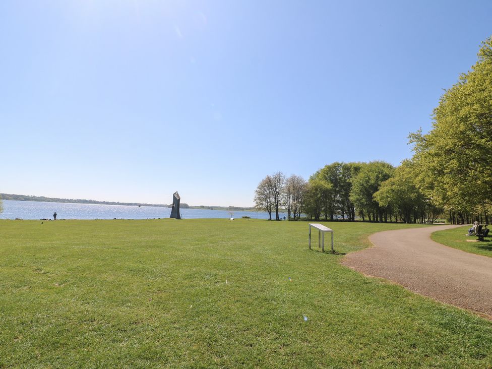 A park with a lake, trees, and a pathway at Gardener’s Cottage, Oakham