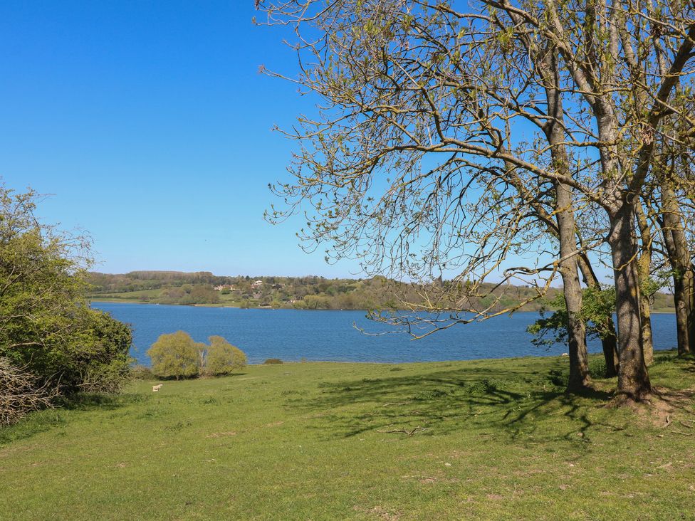 A lake surrounded by trees and grass at Gardener’s Cottage in Oakham