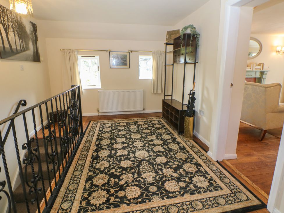 A hallway with a rug and coat rack at Ivy Cottage in Matlock