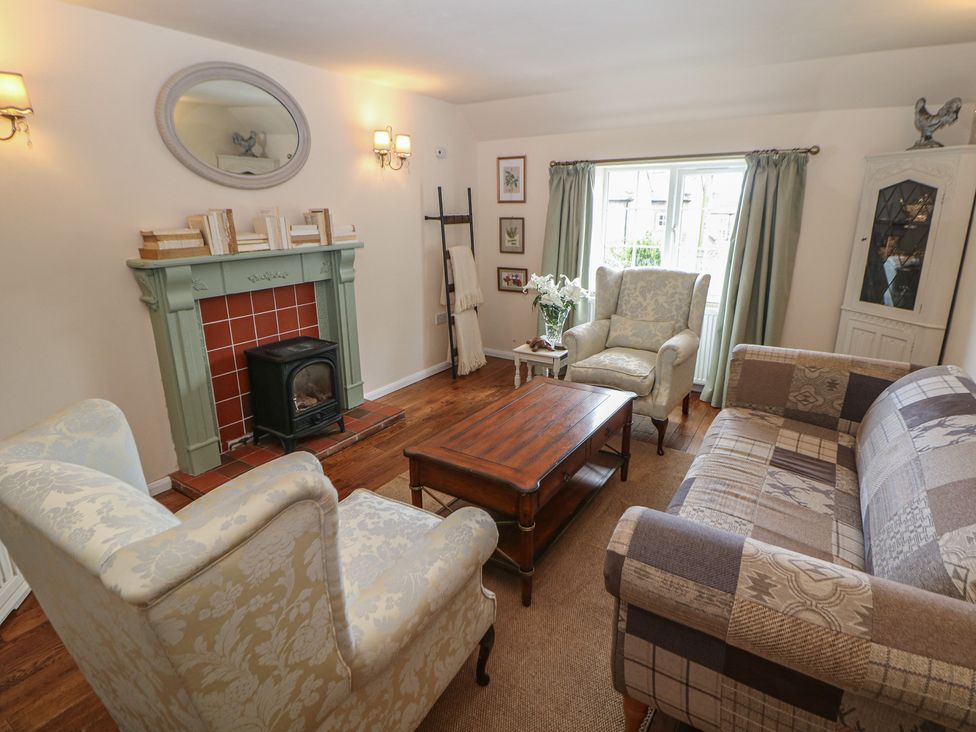 A living room with a fireplace and two armchairs at Ivy Cottage in Matlock
