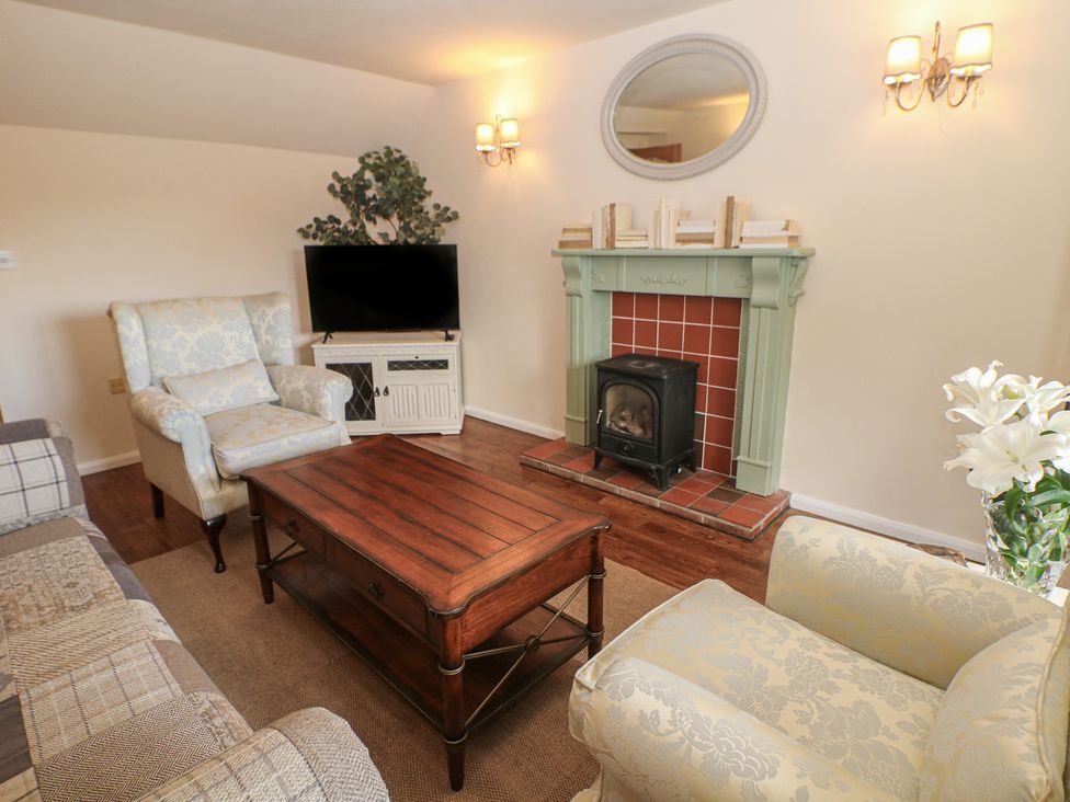 A living room with a television and fireplace at Ivy Cottage in Matlock