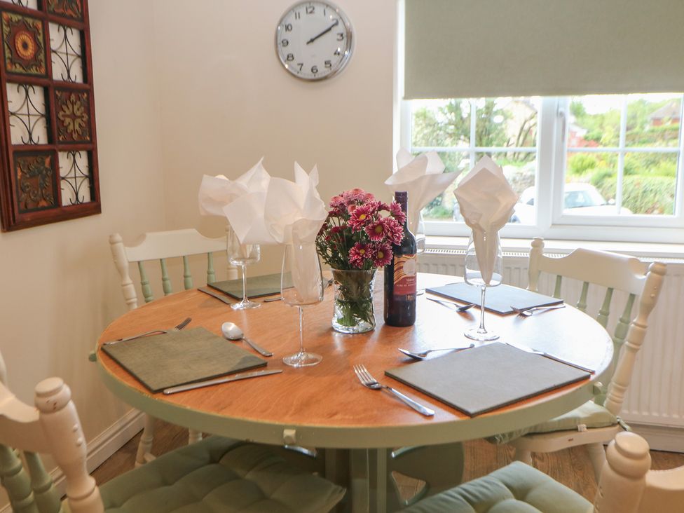 A dining table set with flowers and wine at Ivy Cottage in Matlock