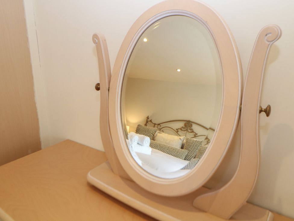 A mirror reflecting furniture in a bedroom at Ivy Cottage Matlock