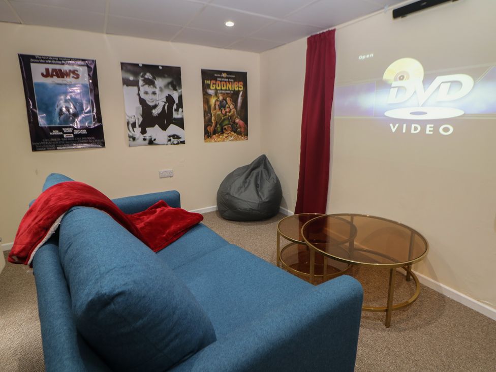 A snug with a blue sofa and posters on the wall at Ivy Cottage Matlock