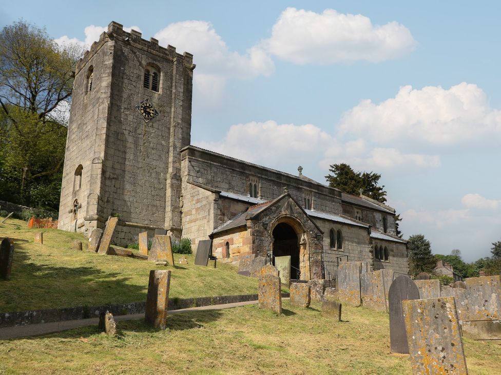 A church with a graveyard and trees at Ivy Cottage in Matlock
