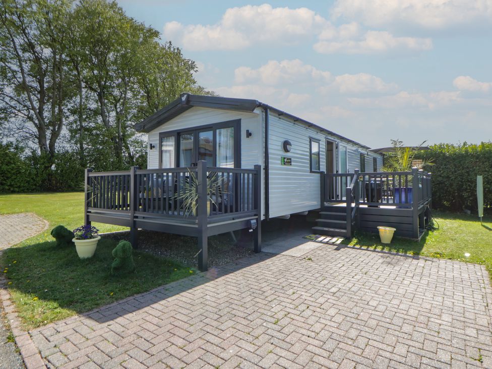 A caravan with decking and surrounded by grass at Santa Maria in Llandysul