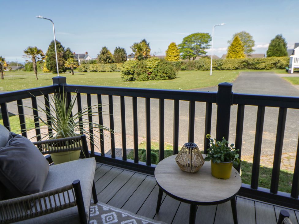A patio area with a table and chairs overlooking a garden at Santa Maria in Llandysul