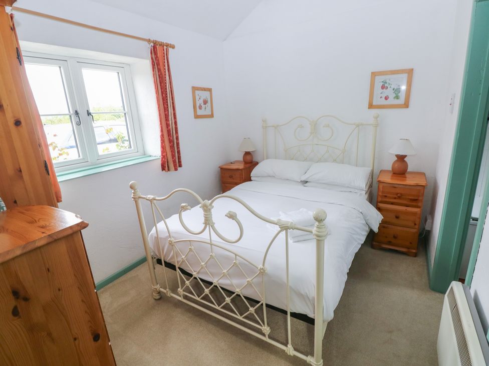 A bedroom with a bed and nightstands at Starling Cottage Cowbridge
