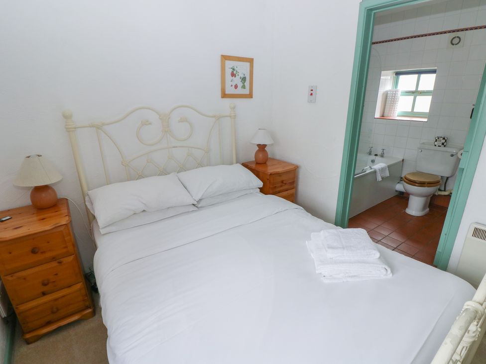 A bedroom with a bed and an adjoining bathroom at Starling Cottage in Cowbridge