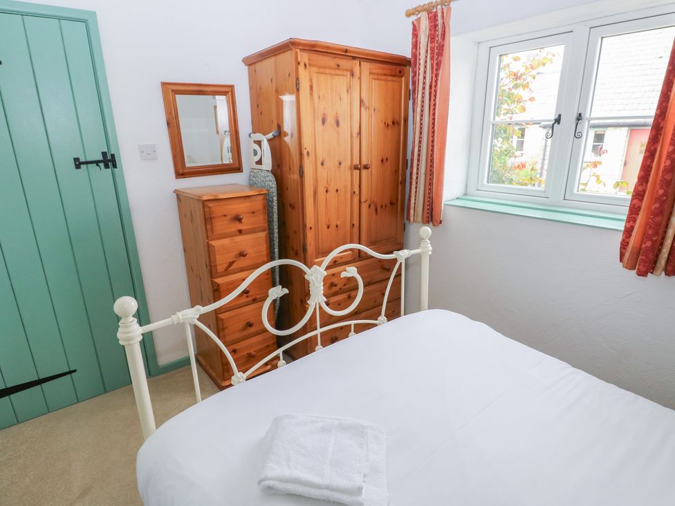 A bedroom with a bed and wardrobe at Starling Cottage in Cowbridge