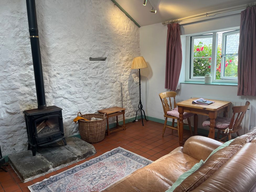A living room with a stove, basket, and table at Starling Cottage near Cowbridge