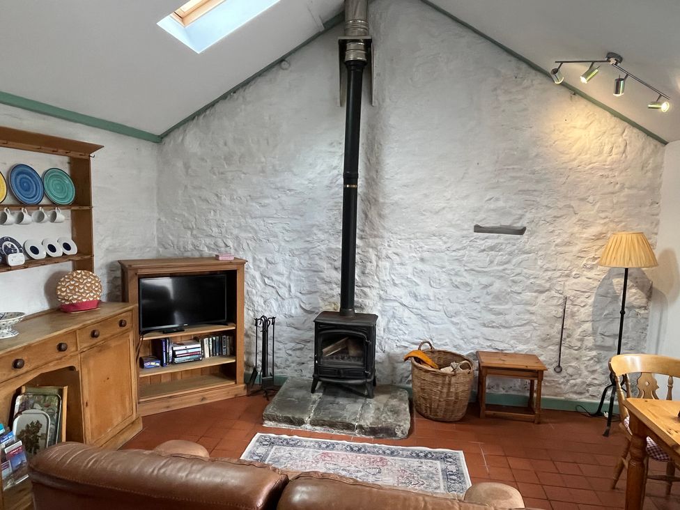 A snug with a wood-burning stove and television at Starling Cottage near Cowbridge