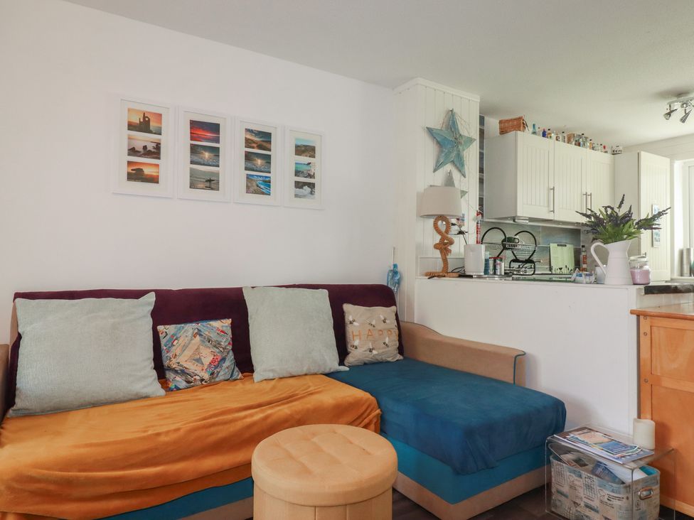 A living room with a sofa and kitchen counter at 140 Atlantic Reach Newquay