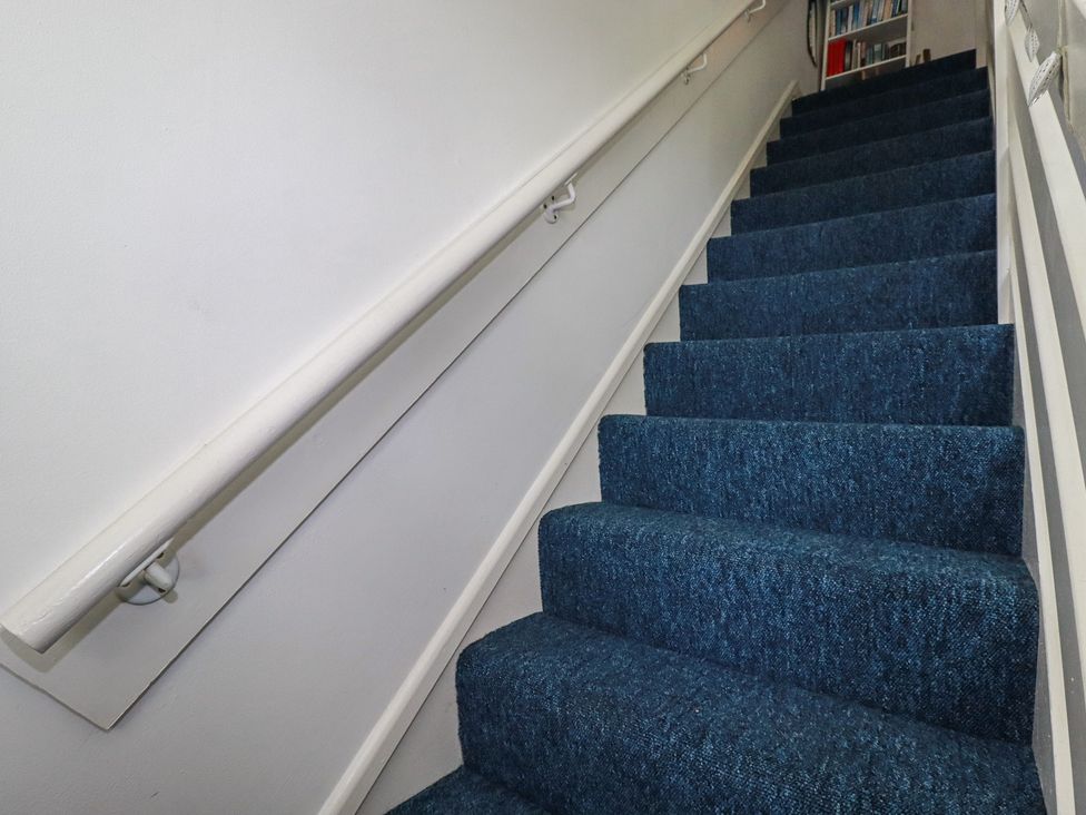 A staircase with blue carpet and a handrail at 140 Atlantic Reach, Newquay