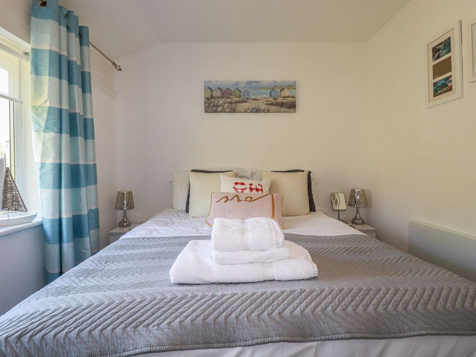 A bedroom with a bed, cushions, and wall art at 140 Atlantic Reach in Newquay