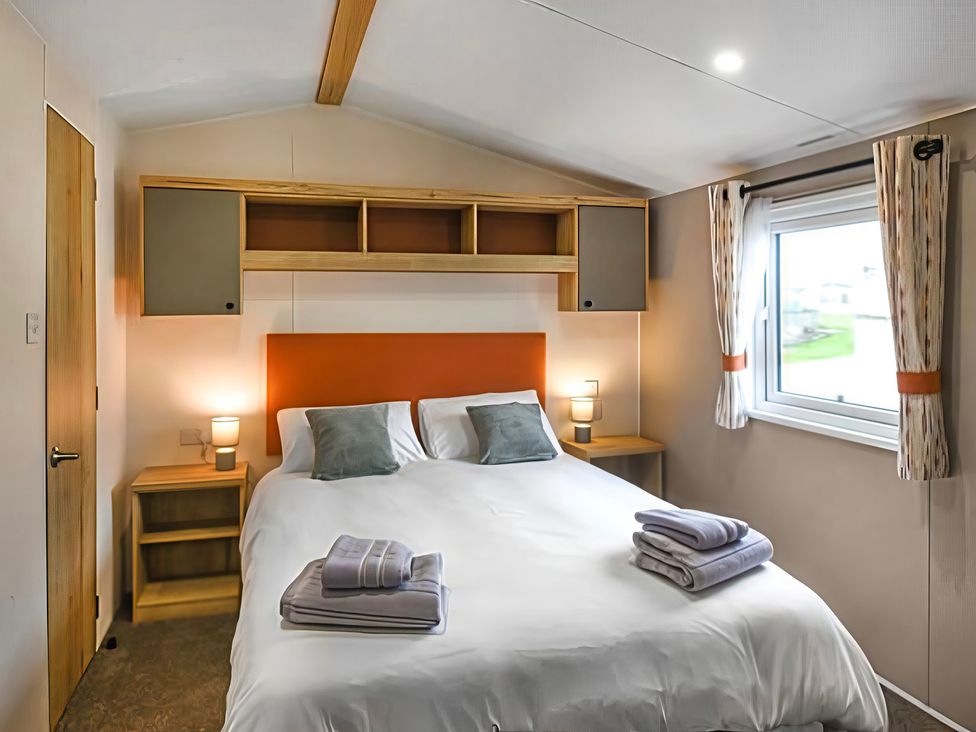 A bedroom with a bed and bedside tables at 26 Ocean View in Llwyngwril