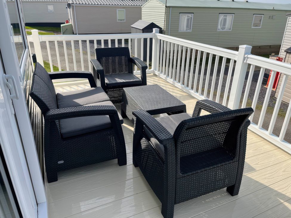 A seating area with chairs and a table on the deck at 26 Ocean View in Llwyngwril