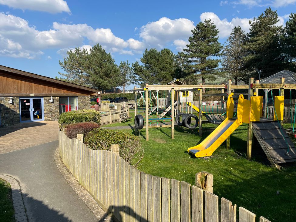 An outdoor playground with slides and swings at 26 Ocean View in Llwyngwril