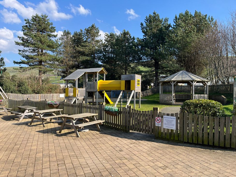 An outdoor play area with playground equipment and seating at 26 Ocean View in Llwyngwril