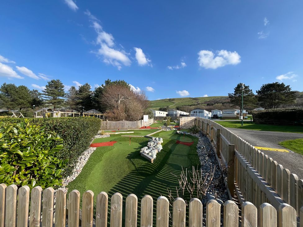 A landscaped area with grass and trees at 26 Ocean View Llwyngwril
