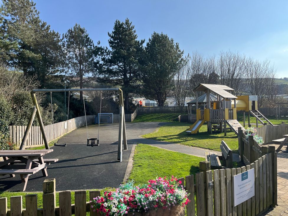 A playground with swings and a play structure at 26 Ocean View in Llwyngwril