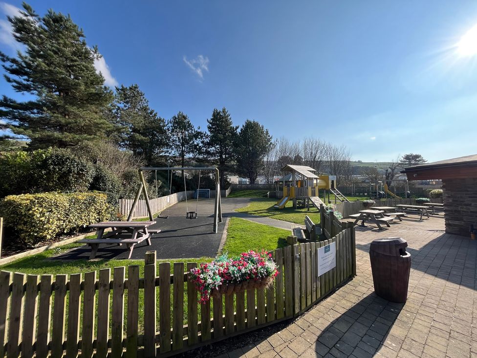 An outdoor playground with swings and a play structure at 26 Ocean View in Llwyngwril