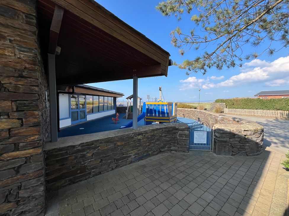 An outdoor area with a playground and stone wall at 26 Ocean View in Llwyngwril