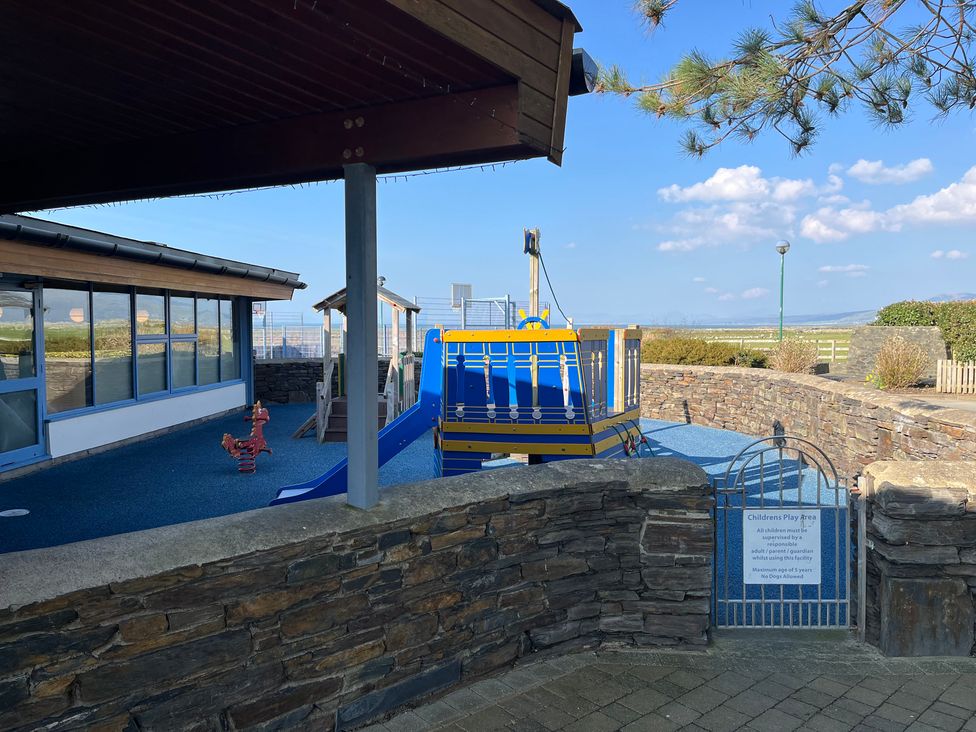 An outdoor play area with a slide and play structure at 26 Ocean View Llwyngwril