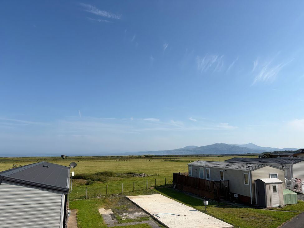 A view of grass and caravans with a mountain in the distance at 26 Ocean View Llwyngwril