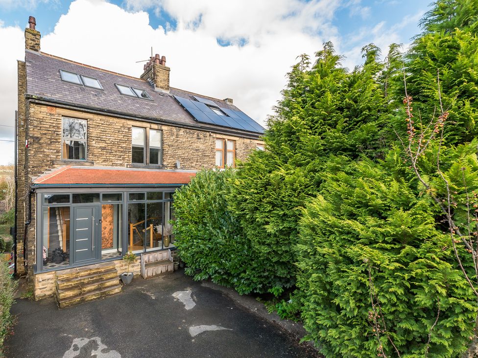 A house with solar panels and trees in front at The Grand Weave House in Shipley