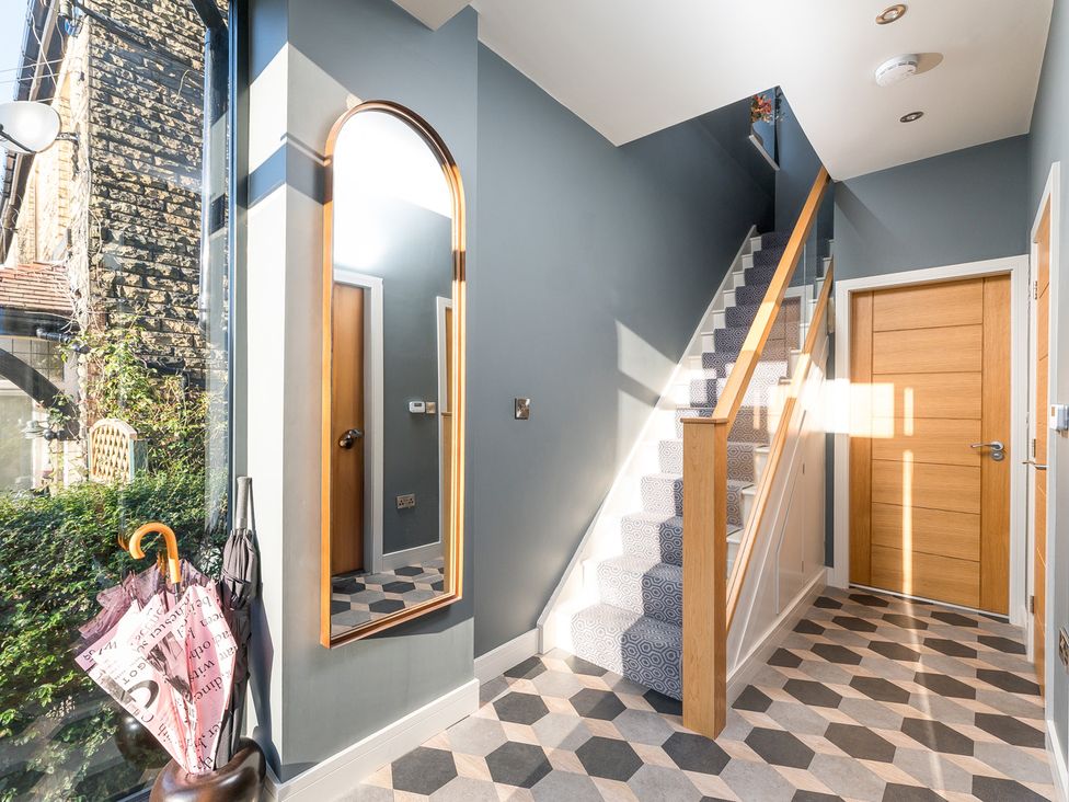 A hallway with stairs and a mirror at The Grand Weave House in Shipley