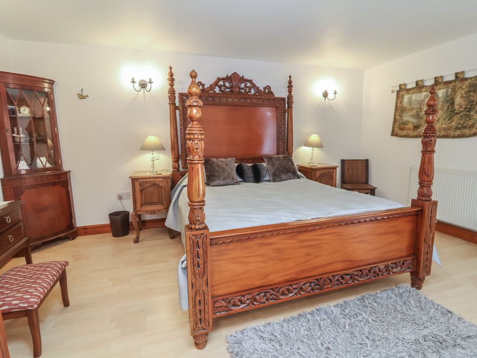 A bedroom with a wooden bed and cabinet at Little Owl Barn, Wellington