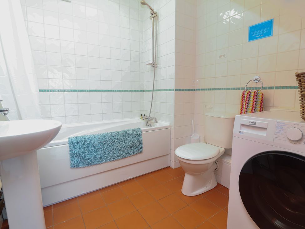 A bathroom with a bathtub, sink, toilet, and washing machine at Little Owl Barn Wellington