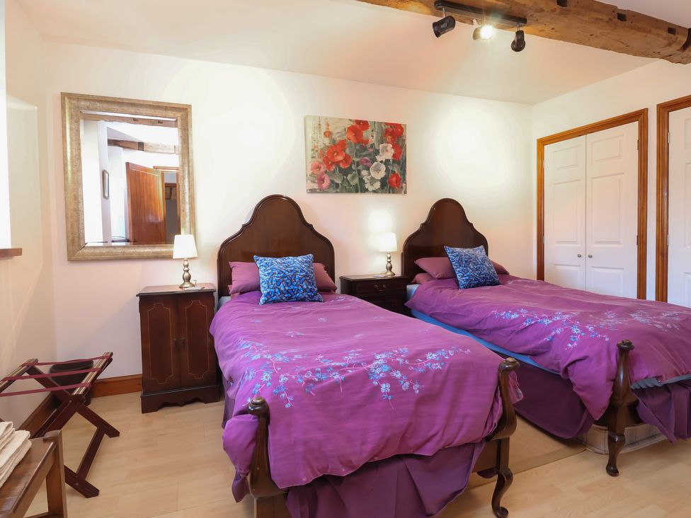 A bedroom with two beds and bedside table at Little Owl Barn Wellington