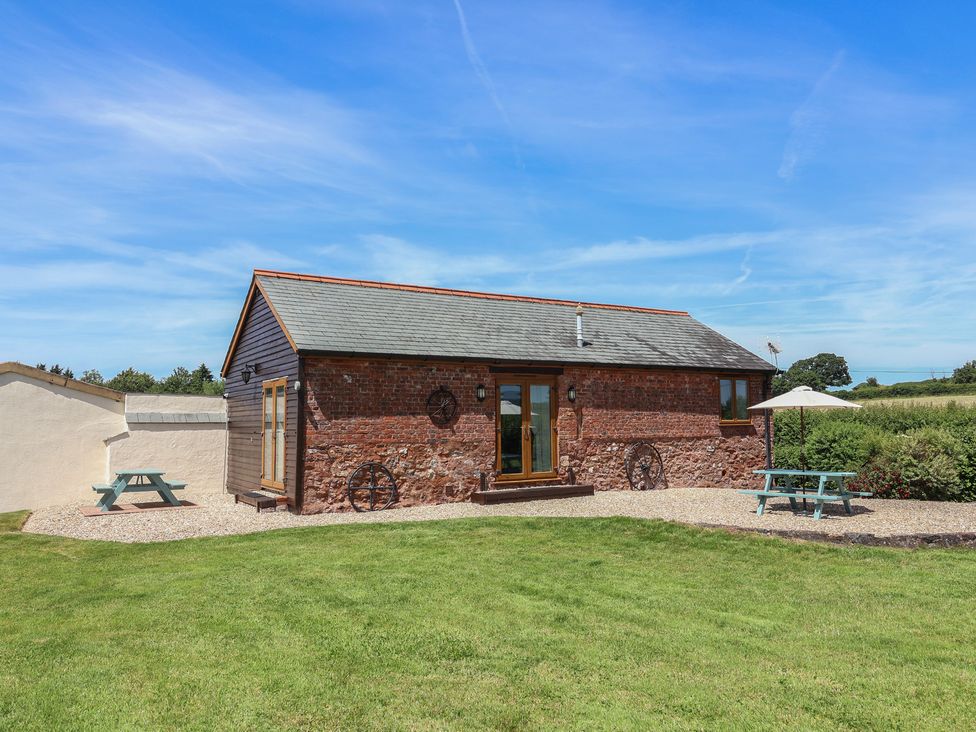 A barn surrounded by grass with a table and umbrella at Little Owl Barn Wellington