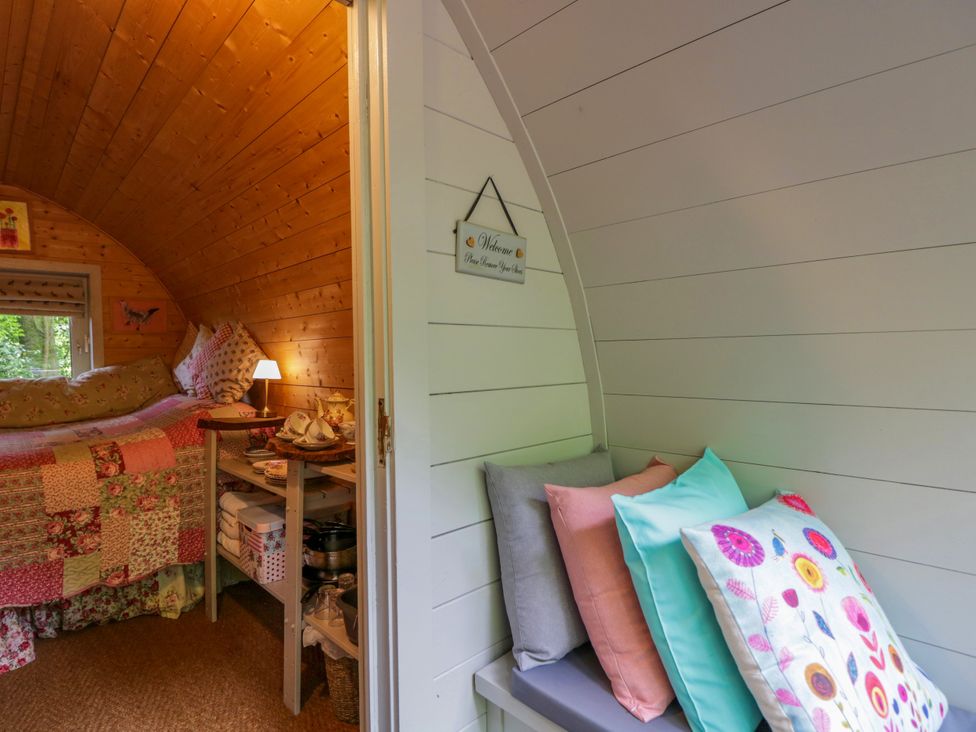 A bedroom with a bed and cushions at Bluebell Glamping Pod in Woolton Hill